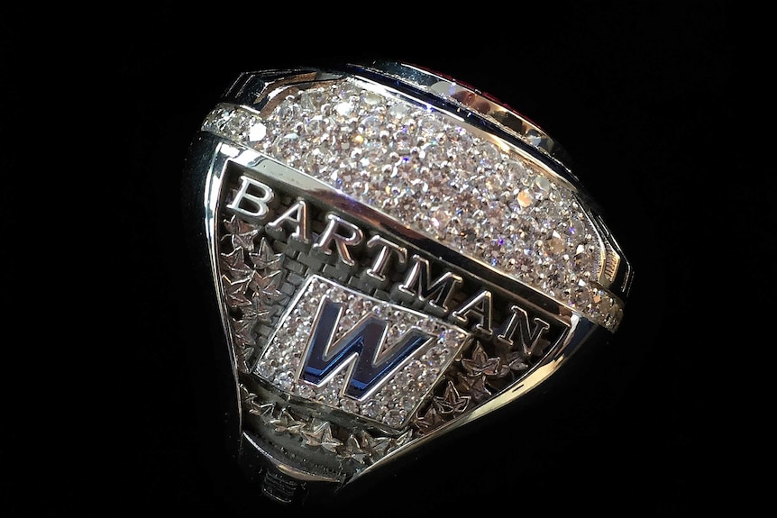 A diamond-encrusted ring with 'BARTMAN' written on it.