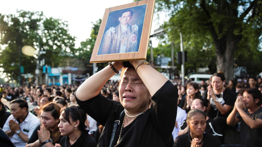 A Thai woman cries as she holds a picture of the late King Bhumibol Adulyadej.