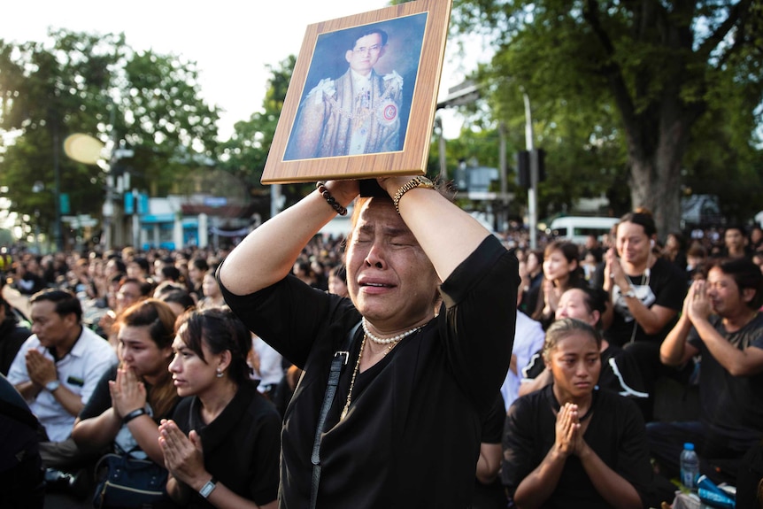 A Thai woman cries as she holds a picture of the late King Bhumibol Adulyadej.