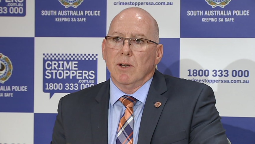 A man in a suit and tie in front of a blue and white backdrop