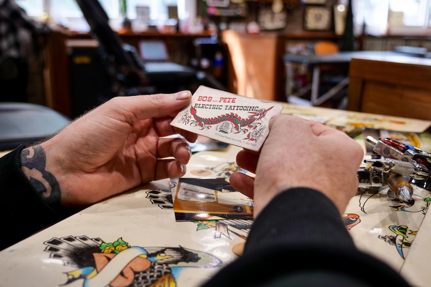 Two hands hold business card labelled Bob & Pete Electric Tattooing.