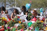 Mourners pay tribute at a school shooting memorial covered with flowers.