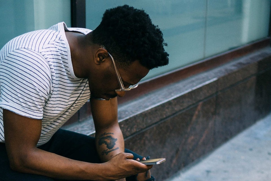 A lonely man looks at his smartphone to depict what to do when you feel lonely during holiday season.