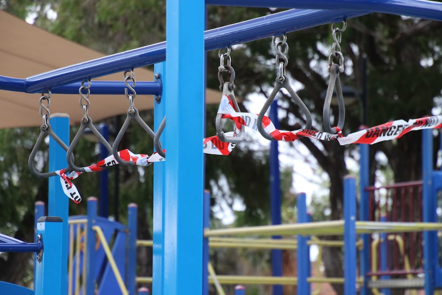 Playground swings and monkey bars with danger tape wrapped around it