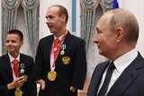 Russian President Vladimir Putin stands with Paralympians at a reception in an opulent room.