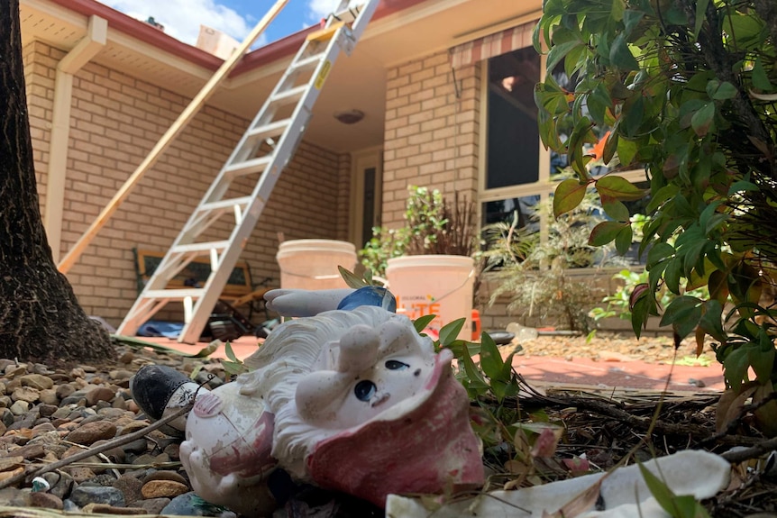 View of smashed garden gnome in garden damaged by storms