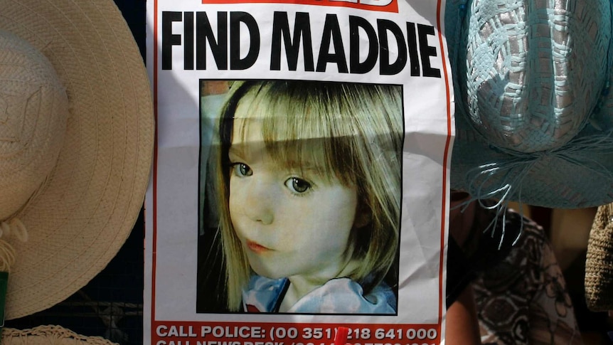 A poster of missing girl Madeleine McCann hangs between sun hats at a stall.