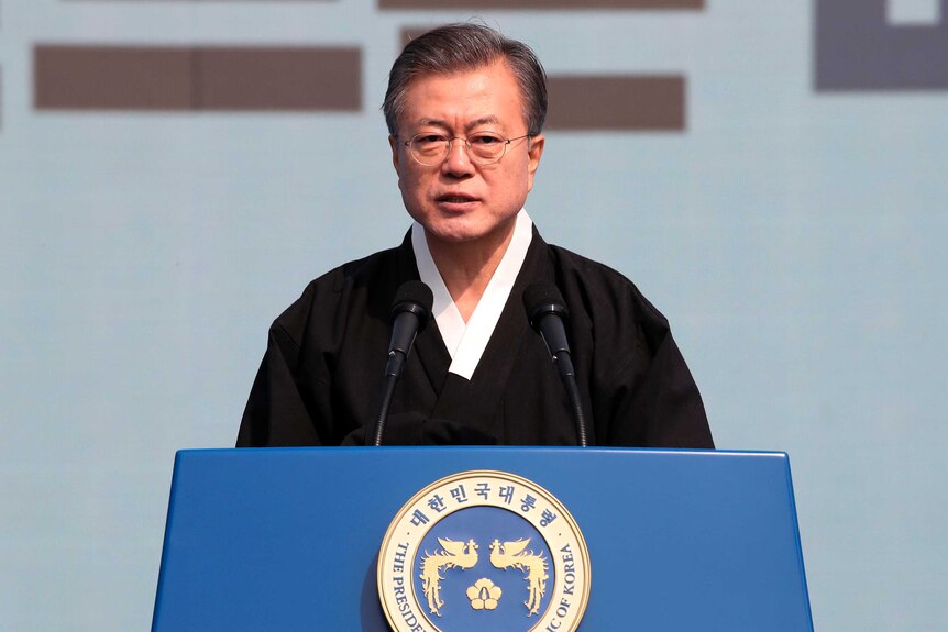 South Korean President Moon Jae-in in traditional Korean black dress in front of a blue Republic of Korea lectern.
