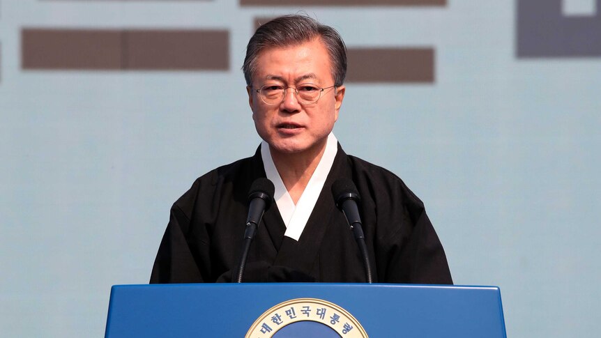 South Korean President Moon Jae-in in traditional Korean black dress in front of a blue Republic of Korea lectern.