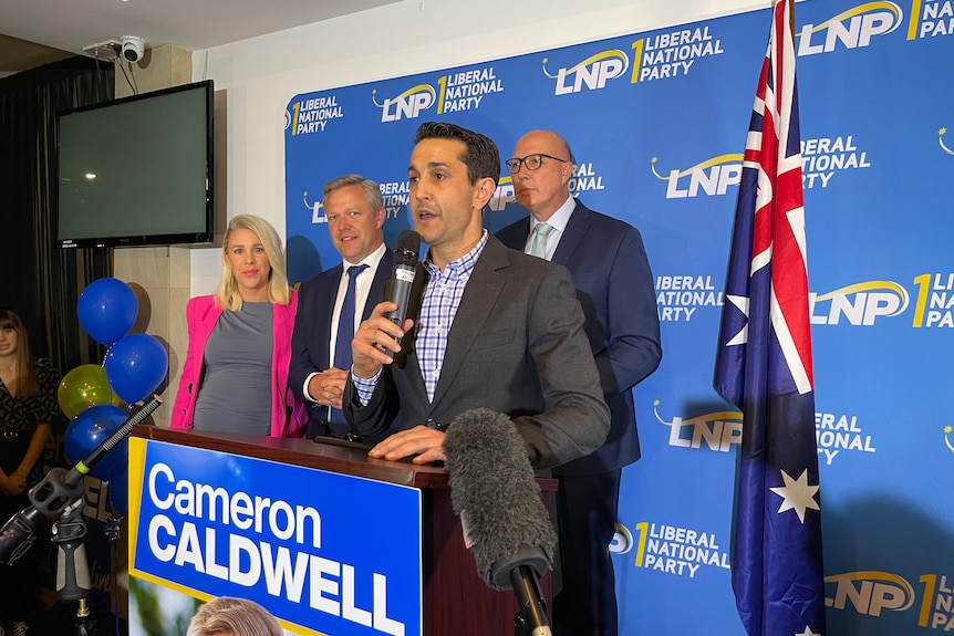 Three men and a woman stand on stage at a LNP victory party