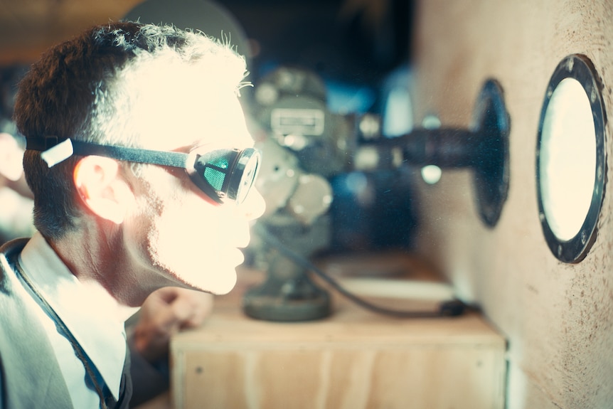 Una película que todavía muestra el perfil lateral de un hombre que lleva gafas. 