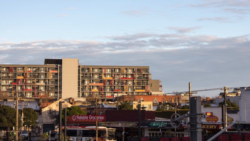 An apartment block, shops and buses in foreground