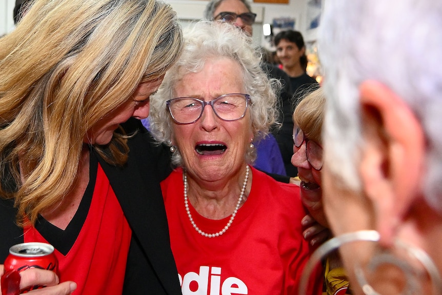 Jodie Belyea abrazando a una mujer mayor con una sonrisa en el rostro. 