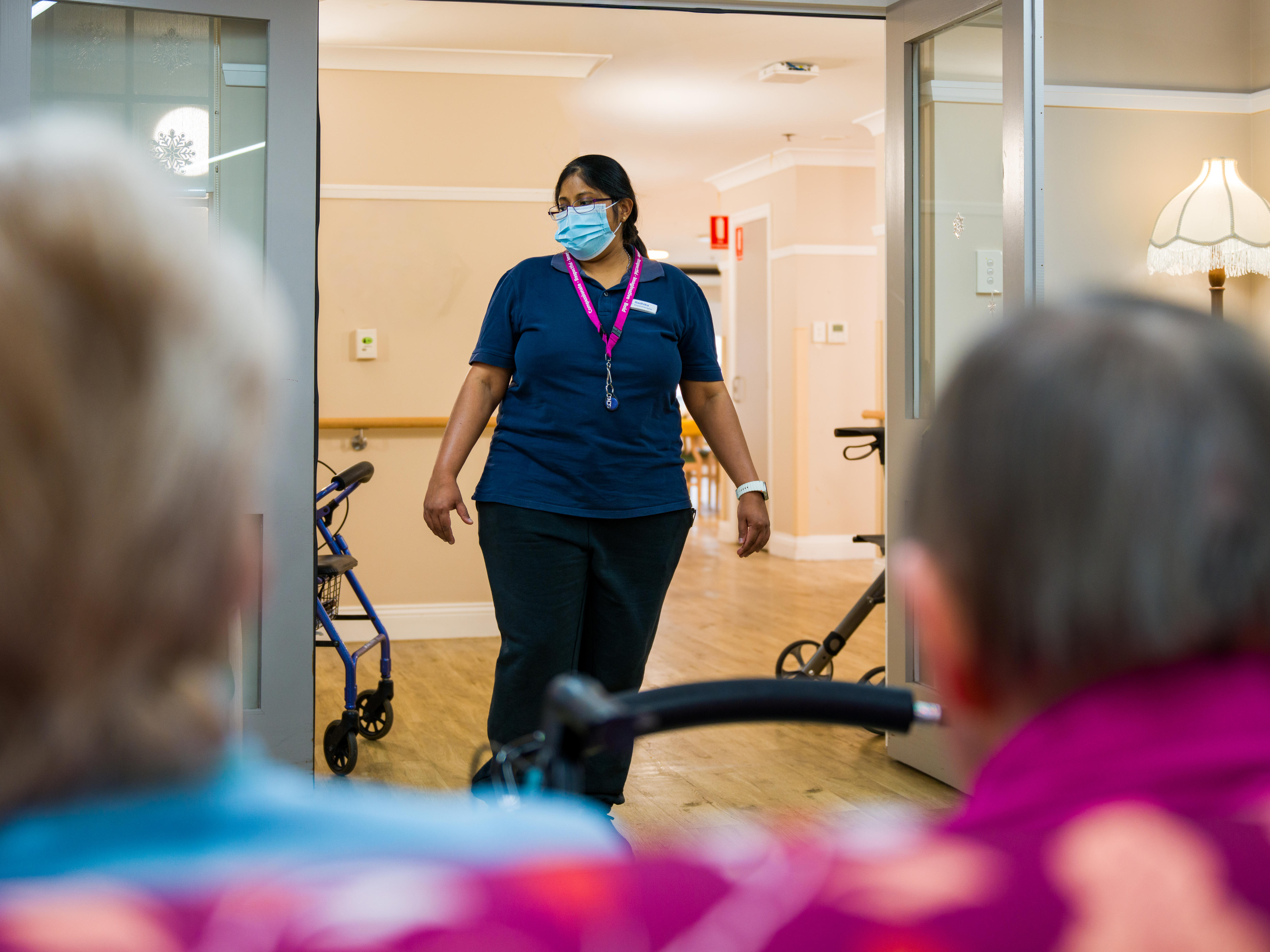 An aged care worker walks into a room with residents.