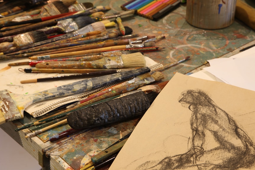 Paint on a table in an art studio with a sketch in the foreground