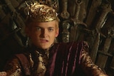 King Joffrey from the Game of Thrones TV show sits on the throne.