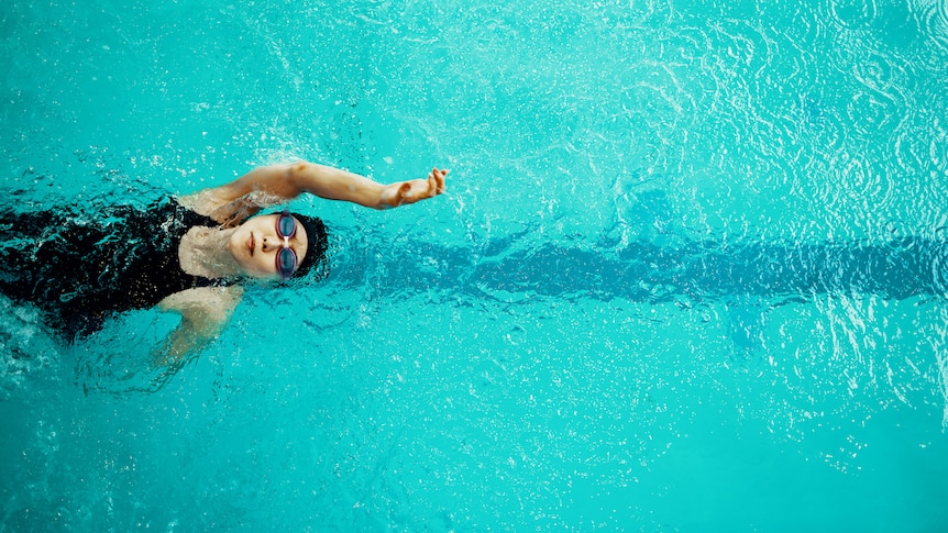 View from directly above a woman training in a pool for competitive swimming.