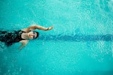 View from directly above a woman training in a pool for competitive swimming.