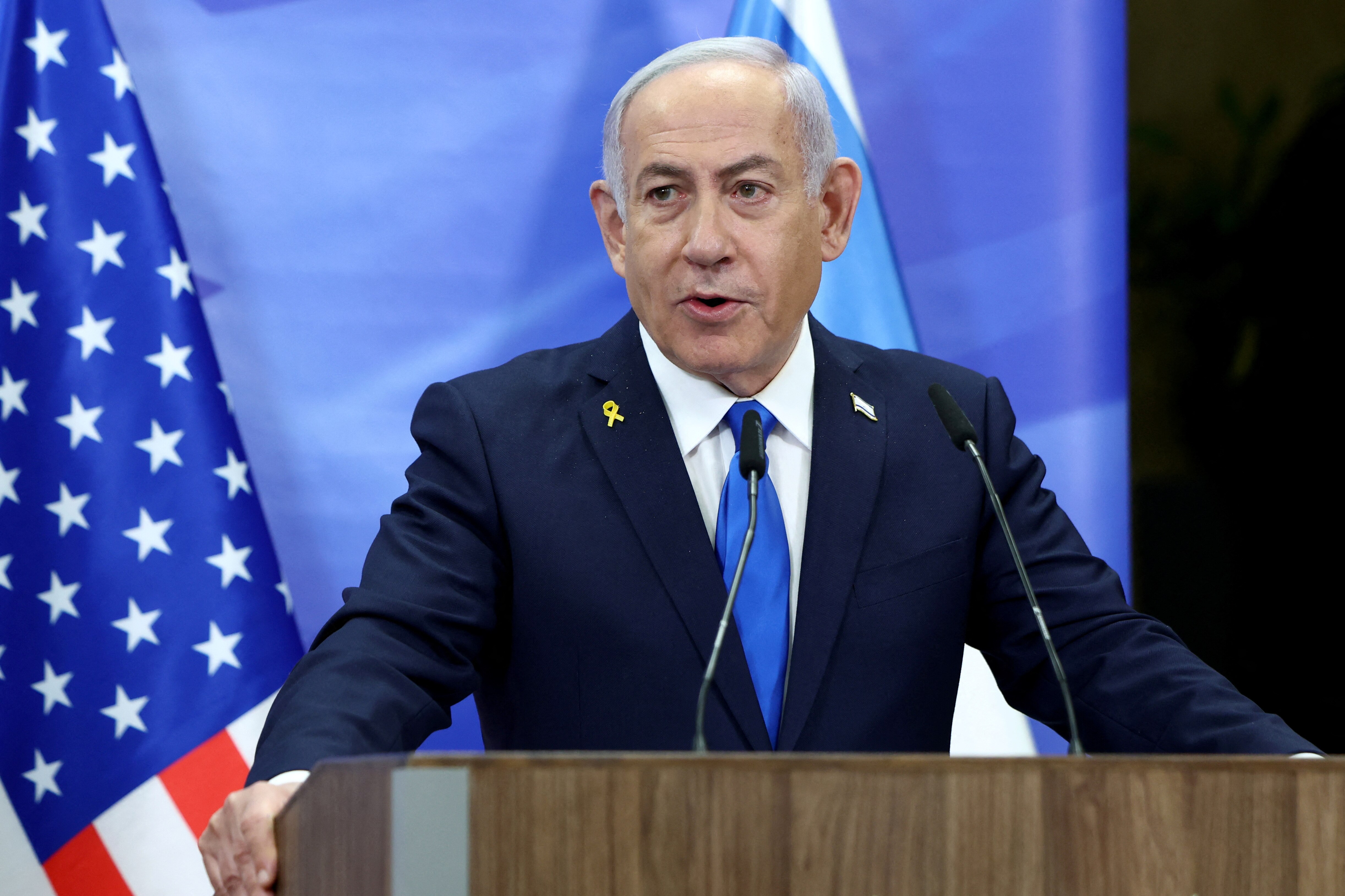 Israeli Prime Minister Benjamin Netanyahu at a press conference, in front of the Israeli and American flags.
