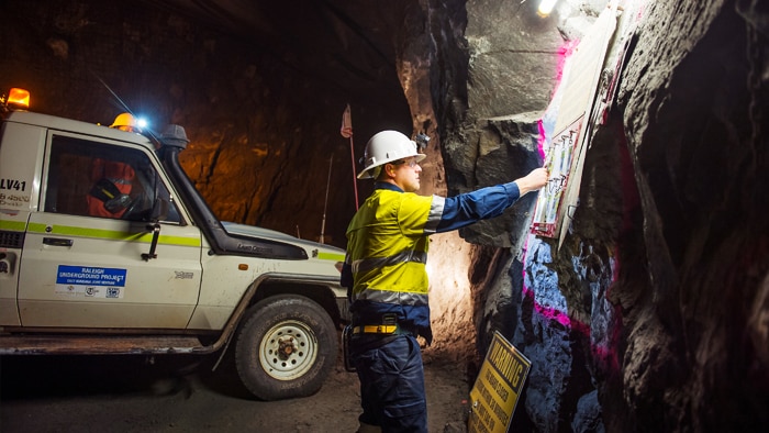 A mine worker next to a ute underground.