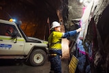 A mine worker next to a ute underground.