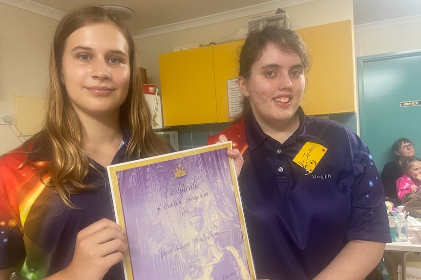 Two young females holding a certificate and smiling