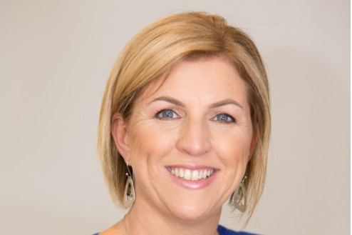 Smiling woman with blonde hair and blue blouse. 