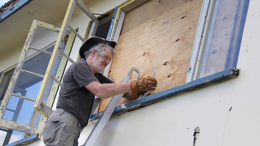 Mick Barker fixes a window at his home after the cyclone