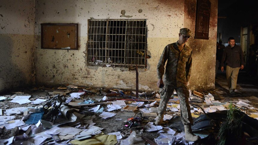 A Pakistani soldier walks amidst the debris in an army-run school a day after an attack by Taliban militants in Peshawar on December 17, 2014.