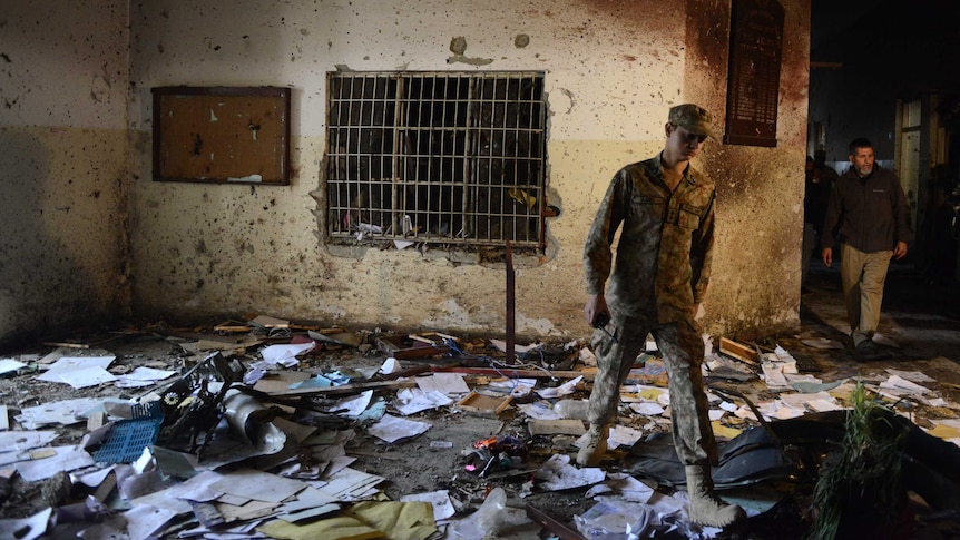 A Pakistani soldier walks amidst the debris in an army-run school