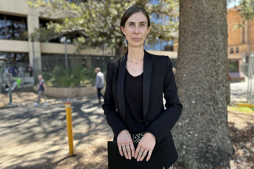 Karly Warner Chief Executive Officer from the Aboriginal Legal Service standing outdoors next to a tree looking at the camera