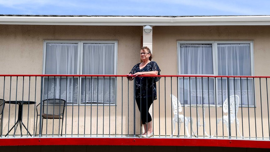 A woman standing at the balcony of a motel