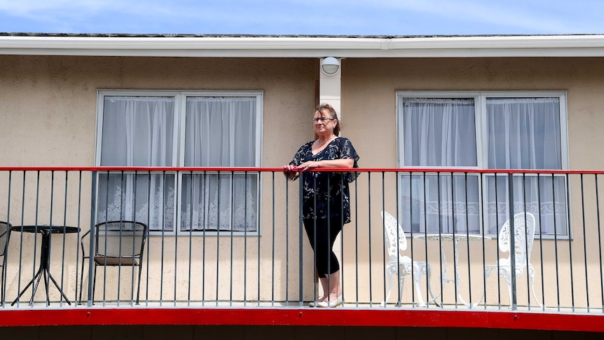 A woman standing at the balcony of a motel