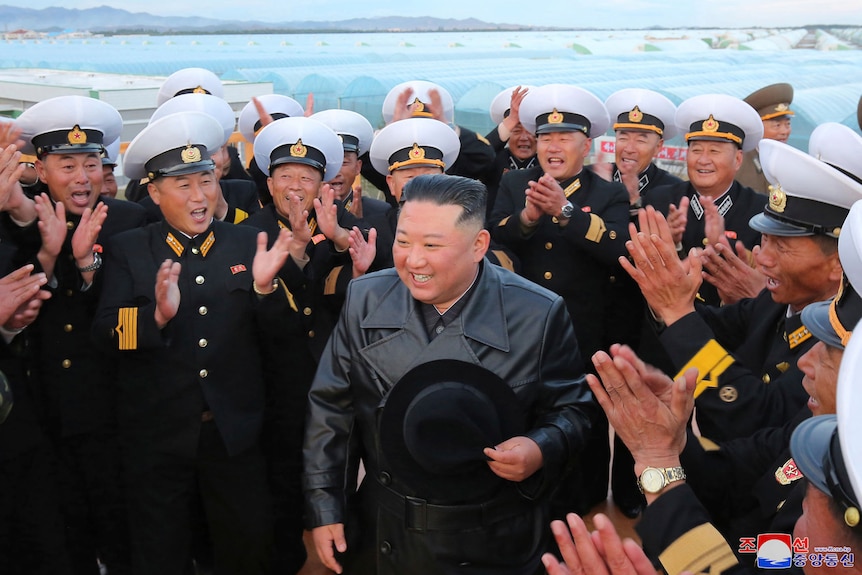 A man gets a rousing round of applause from a group of men wearing military uniforms