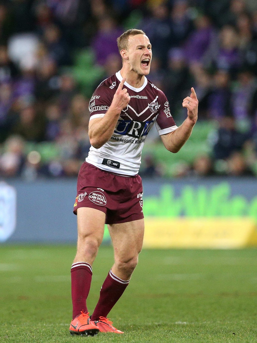 A male NRL player shouts and points his fingers to celebrate kicking the winning field goal.