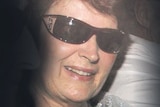 A grainy photo of a woman in dark sunglasses.