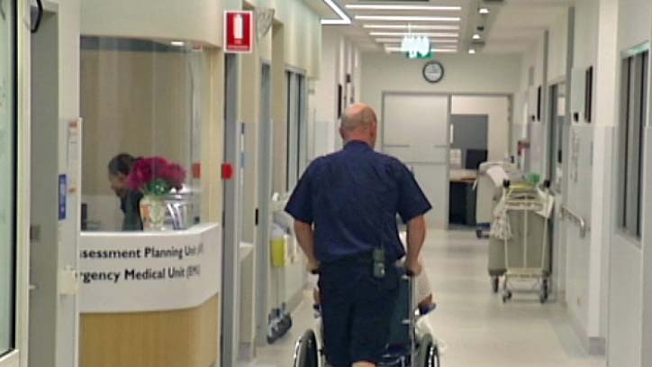 A health worker pushes a patient in a wheelchair in hospital.