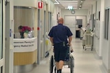 A health worker pushes a patient in a wheelchair in hospital.