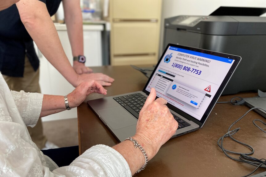 Les mains d'une femme plus âgée sur le clavier et l'écran affichent un avertissement de virus