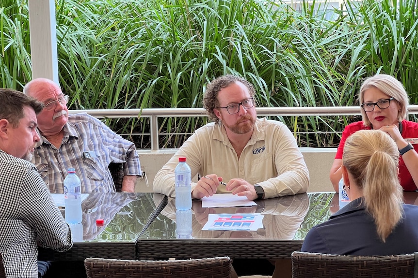 three men and two women in conversation around a table