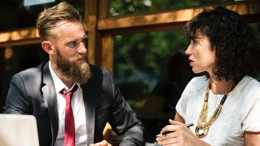 Man and woman having a work-related conflict at a coffee shop outside