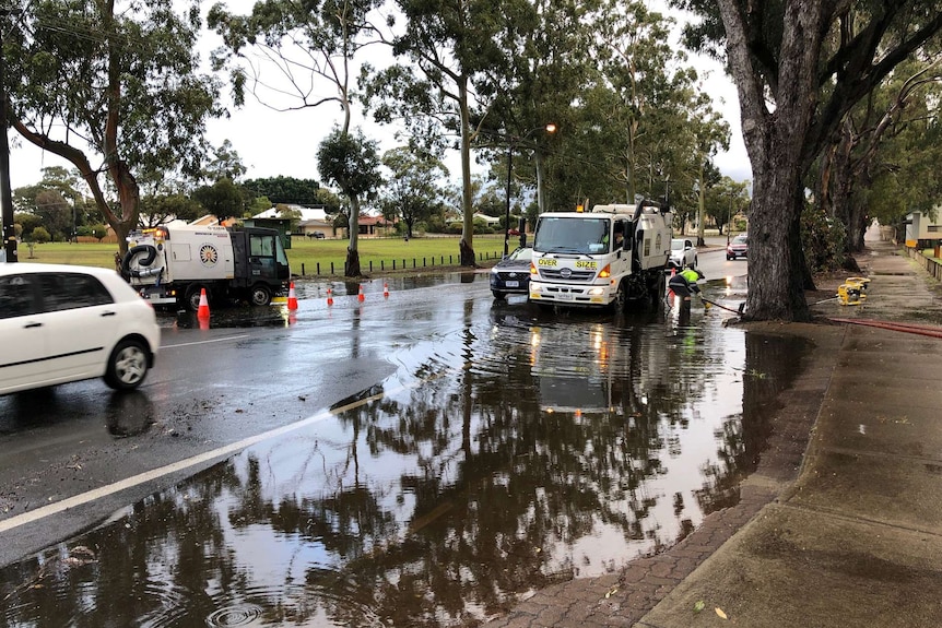 A wide shot of a street in Bayswater with half of the road flooded and a truck pumping water away.