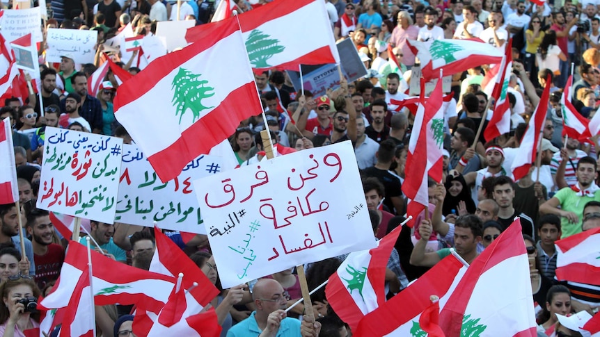 Lebanese hold national flags and placards during a mass rally