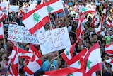 Lebanese hold national flags and placards during a mass rally