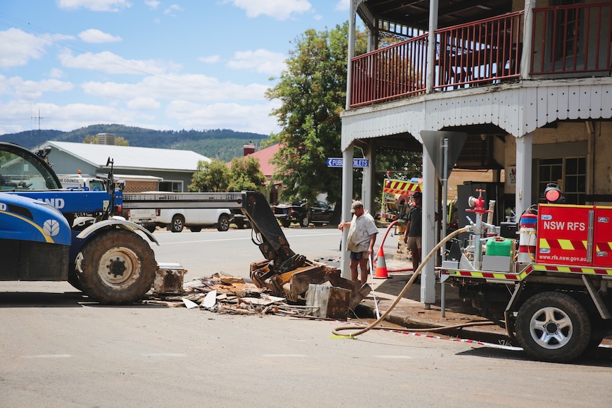 heavy machinery remove debris from a road, outside a pub