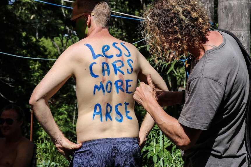 'Less cars more arse' painted on man's back
