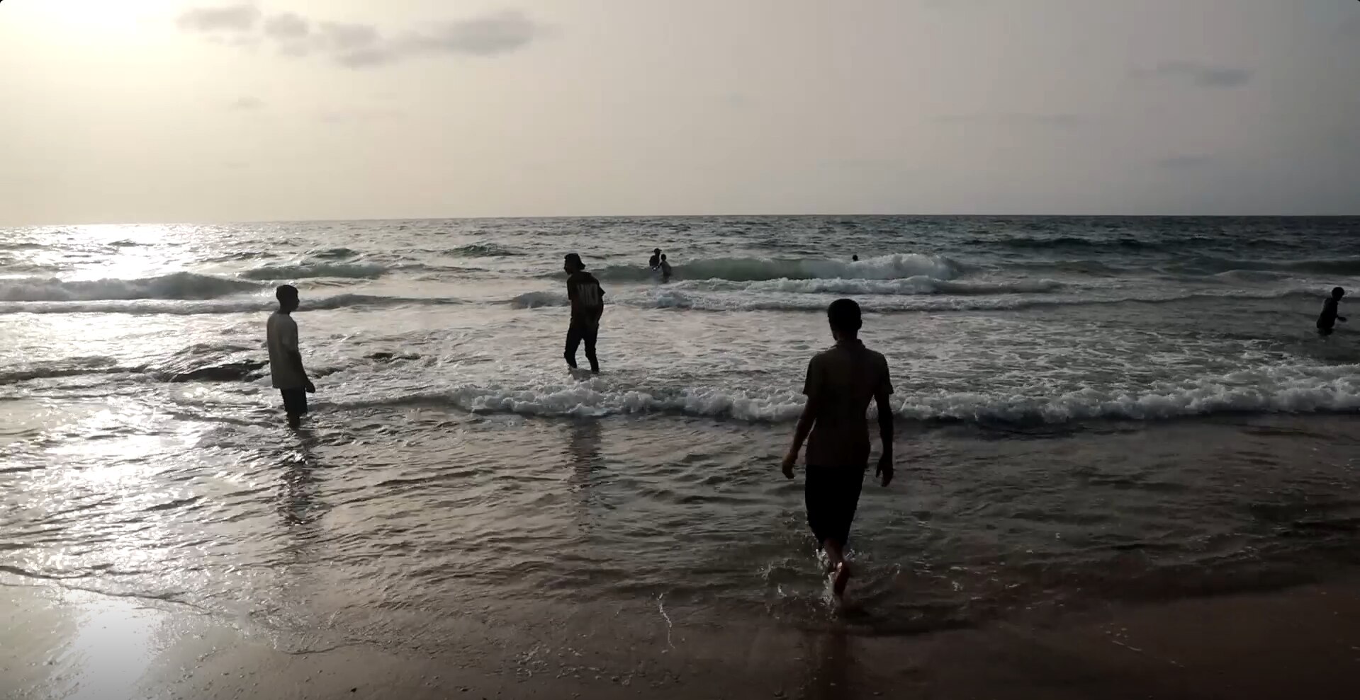 Boys walking along a beach at sunset