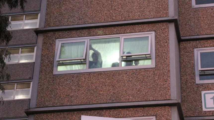 People can be seen gesturing out the window of their housing unit.