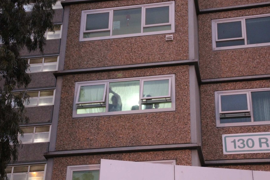 People can be seen gesturing out the window of their housing unit.