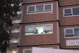 People can be seen gesturing out the window of their housing unit.